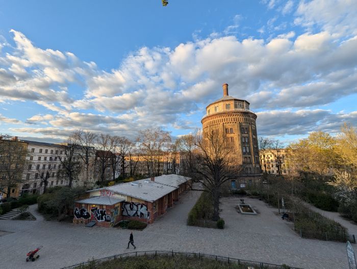 A round brick water tower above a Berlin square at golden hour
