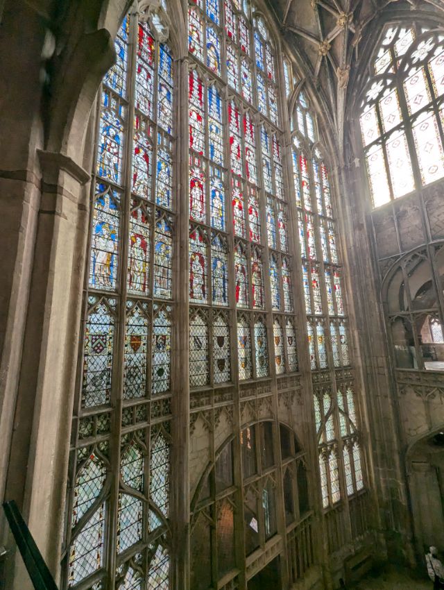 A stained-glass window rising into the vaulting of a church in Gloucester